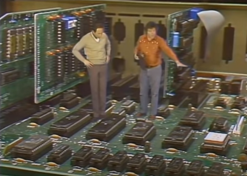 Stewart Cheifet and Bruce Tognazzini standing inside the enlarged interior of an Apple //e.