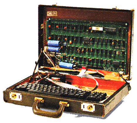 An open briefcase with an Apple I circuit board in the top and an attached keyboard in the bottom.