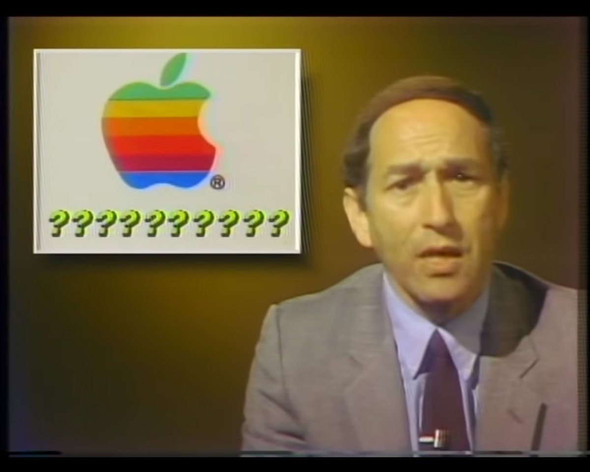 Stewart Cheifet presenting a news story about Apple Computers. In the top right corner is a box with the old six-color Apple logo and a bunch of question marks, &ldquo;??????????&rdquo;